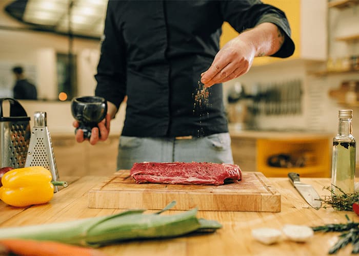 Homem temperando a carne crua em cima de tábua