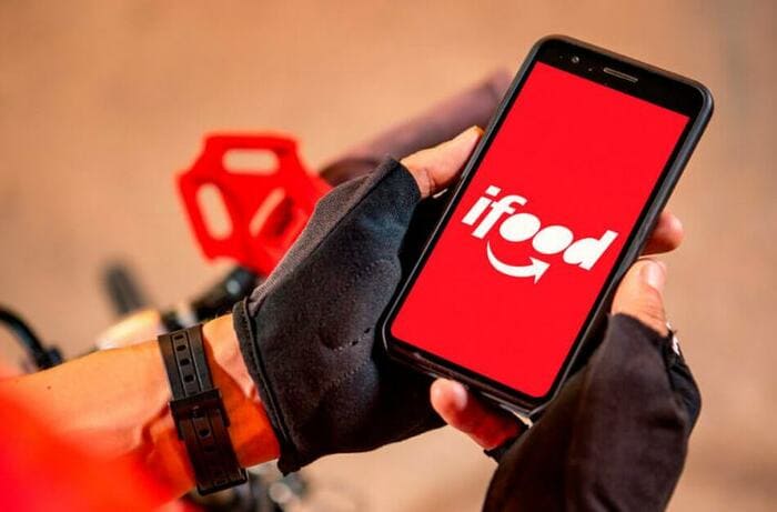 Entregador segurando o celular com a logo do ifood