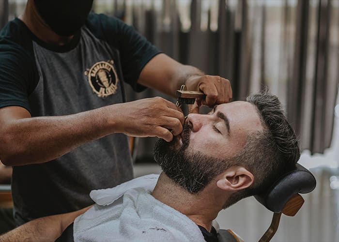 Barbeiro fazendo a barba de cliente