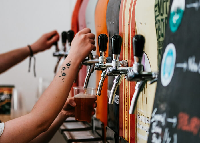 Mãos de clientes se servindo nas torneiras de cerveja disponíveis