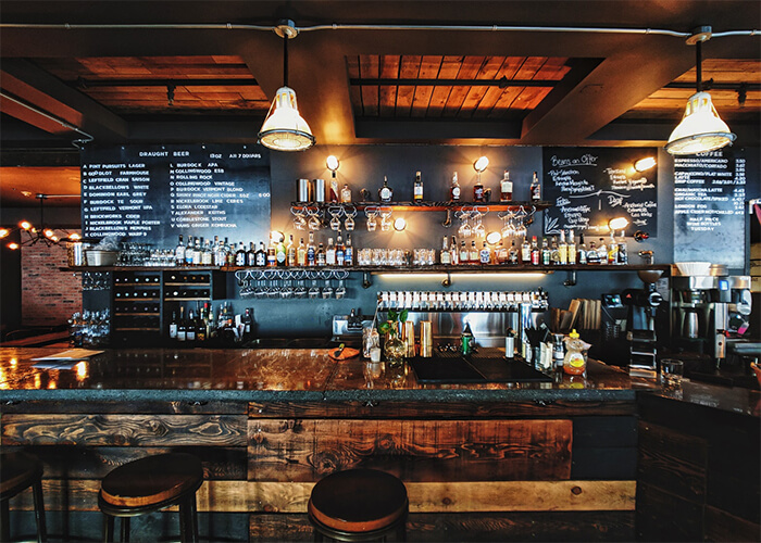  Balcão de Pub em madeira rústica com bebidas e luminárias