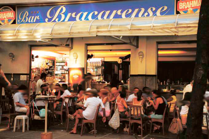 Lado de fora do Bar Bracarense com clientes sentados nas mesas na calçada.