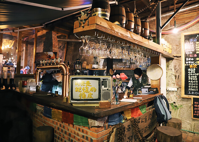 Balcão de bar Oriental com TV antiga, lampião da vó, pipas pequenas e muitos artigos de decoração antiga que compõem o cenário