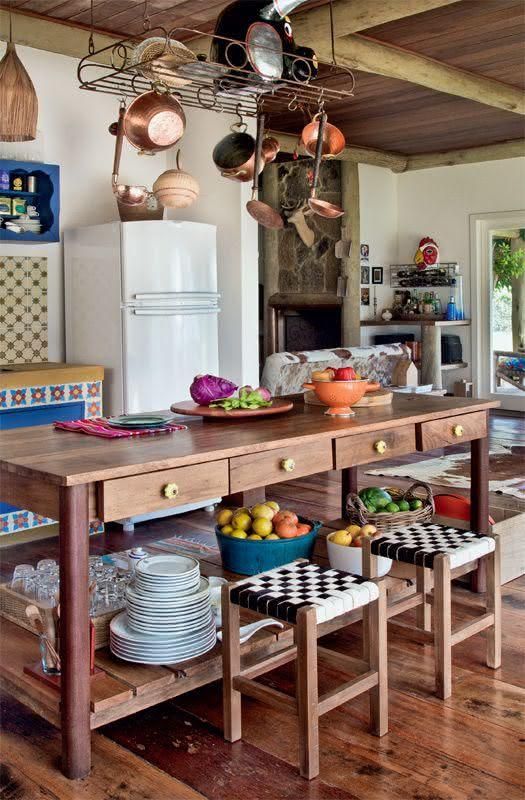 cozinha rústica com ilha de madeira central, com ornamentos e banquetas pequenas de madeira