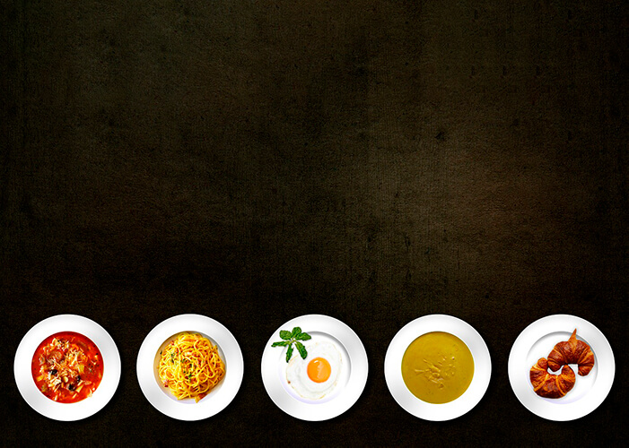 Cinco pratos brancos com comidas diferentes alinhados em fila na parte inferior da foto com fundo marrom dourado