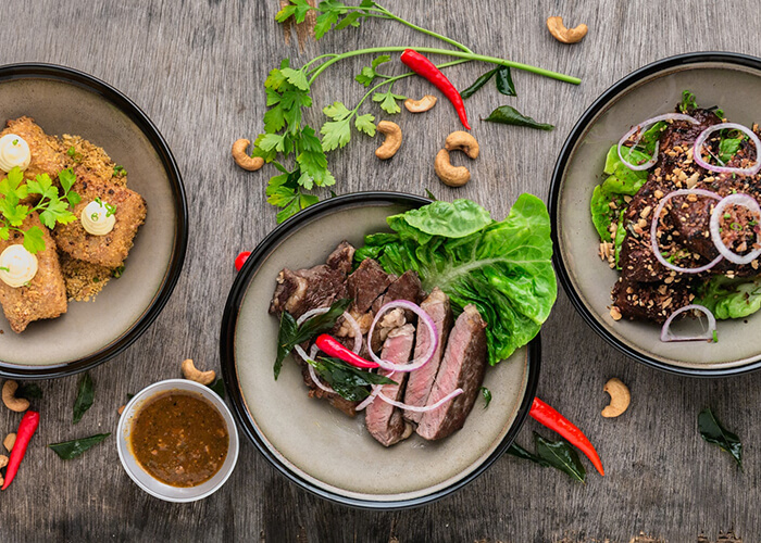 3 pratos vistos de cima com comidas do tipo carnes, saladas.