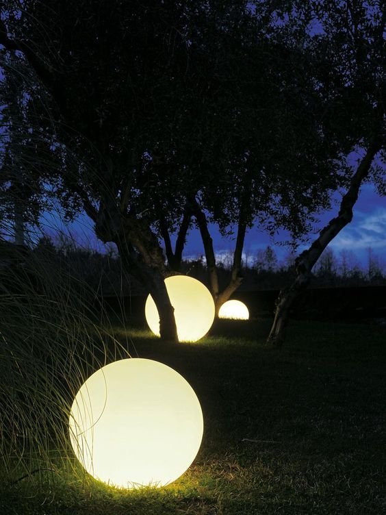 Bolas de LED no meio do gramado com árvores