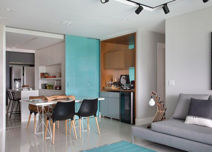 ambiente integrado de sala com cozinha, porta azul de correr separando os dois ambientes