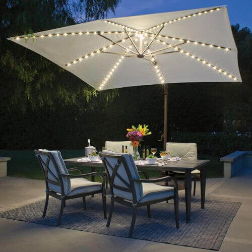 Ambiente externo com mesa e 4 cadeiras e ombrelone iluminado