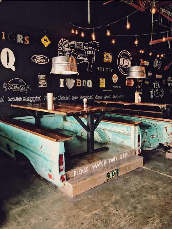 foto de restaurante interno feito com produtos reutilizados como carcaça de carro para dar base a mesa e bancos.