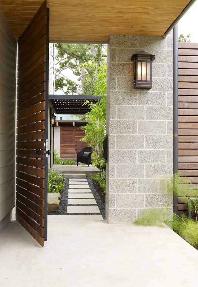 fachada de casa com porta grande de madeira aberta com parede de blocos de cimento