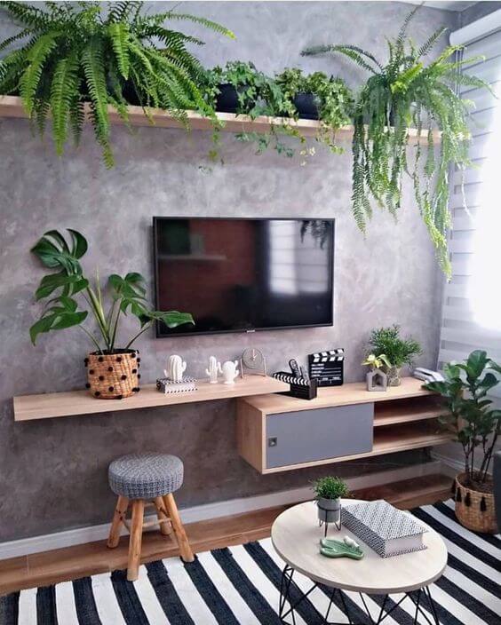  sala de tv com parede cinza e prateleiras de madeira com várias flores