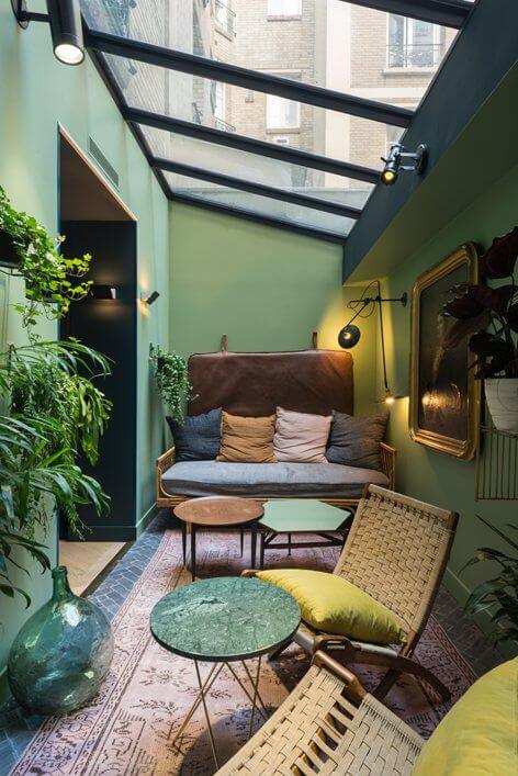 Varanda com paredes verdes, teto transparante e folhagens