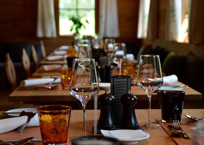 mesas de restaurantes arrumadas com taças, copos, pratos e talheres
