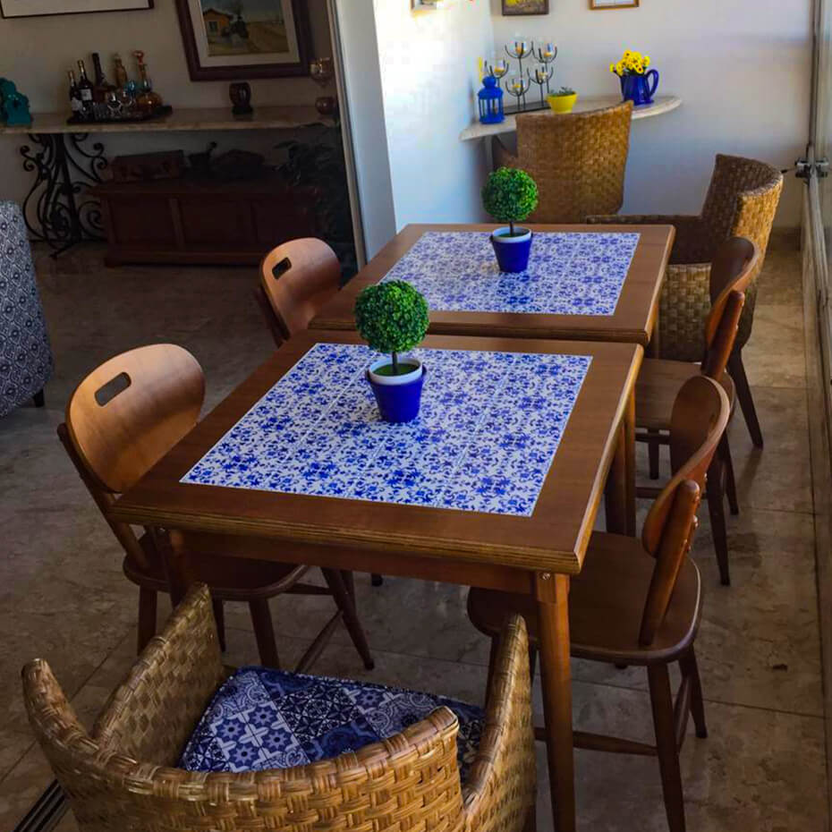 Mesas com estampa de ladrilho português, cadeiras de madeira.