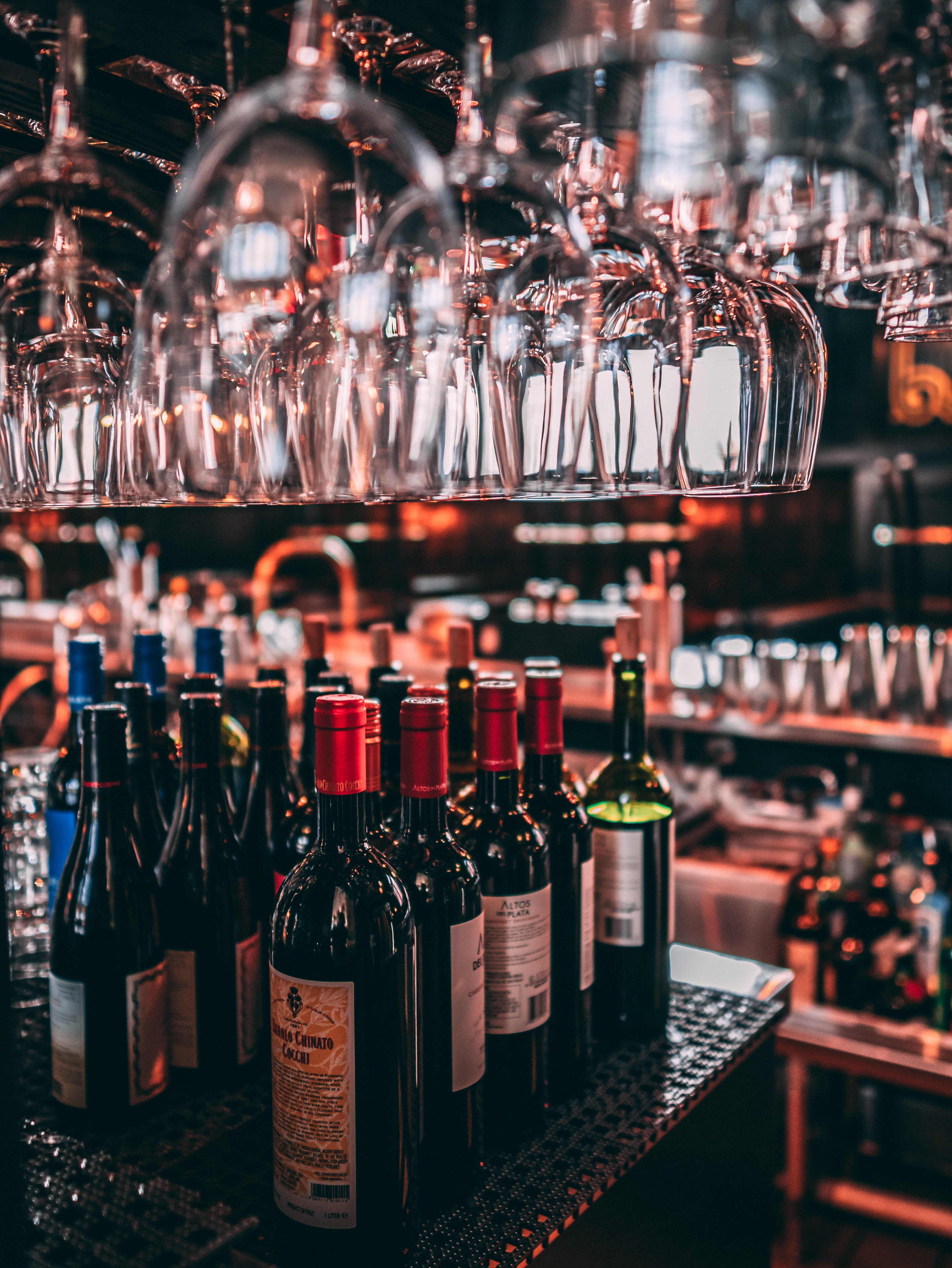 garrafas-de-vinho-em-cima-do-balcao-comvarias-taças-penduradas-acima-das-garrafas