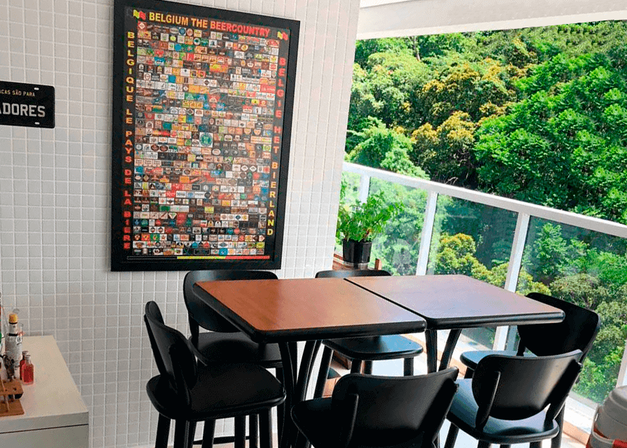 Duas mesas com banquetas em na varanda grande com vista para as árvores