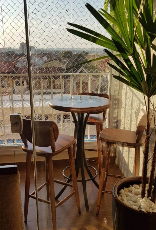 mesa alta com banquetas em uma varanda pequena com uma árvore artificial
